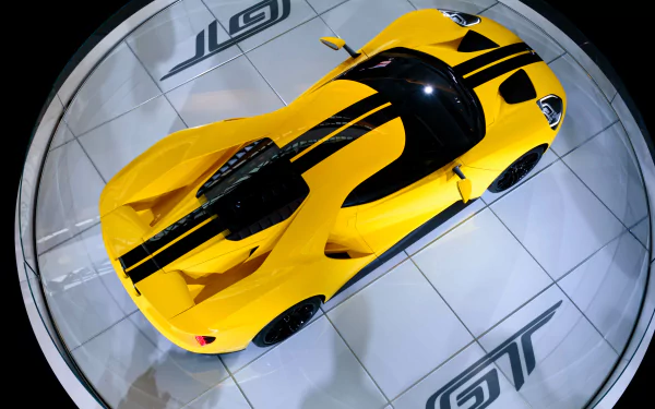 Top-down view of a yellow Ford GT supercar with black racing stripes, showcased as a sleek 4K Ultra HD PC desktop wallpaper and background.
