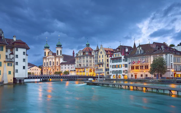Scenic view of historic houses along the river in Lucerne, Switzerland, captured in a high-definition desktop wallpaper showcasing charming man-made architecture.