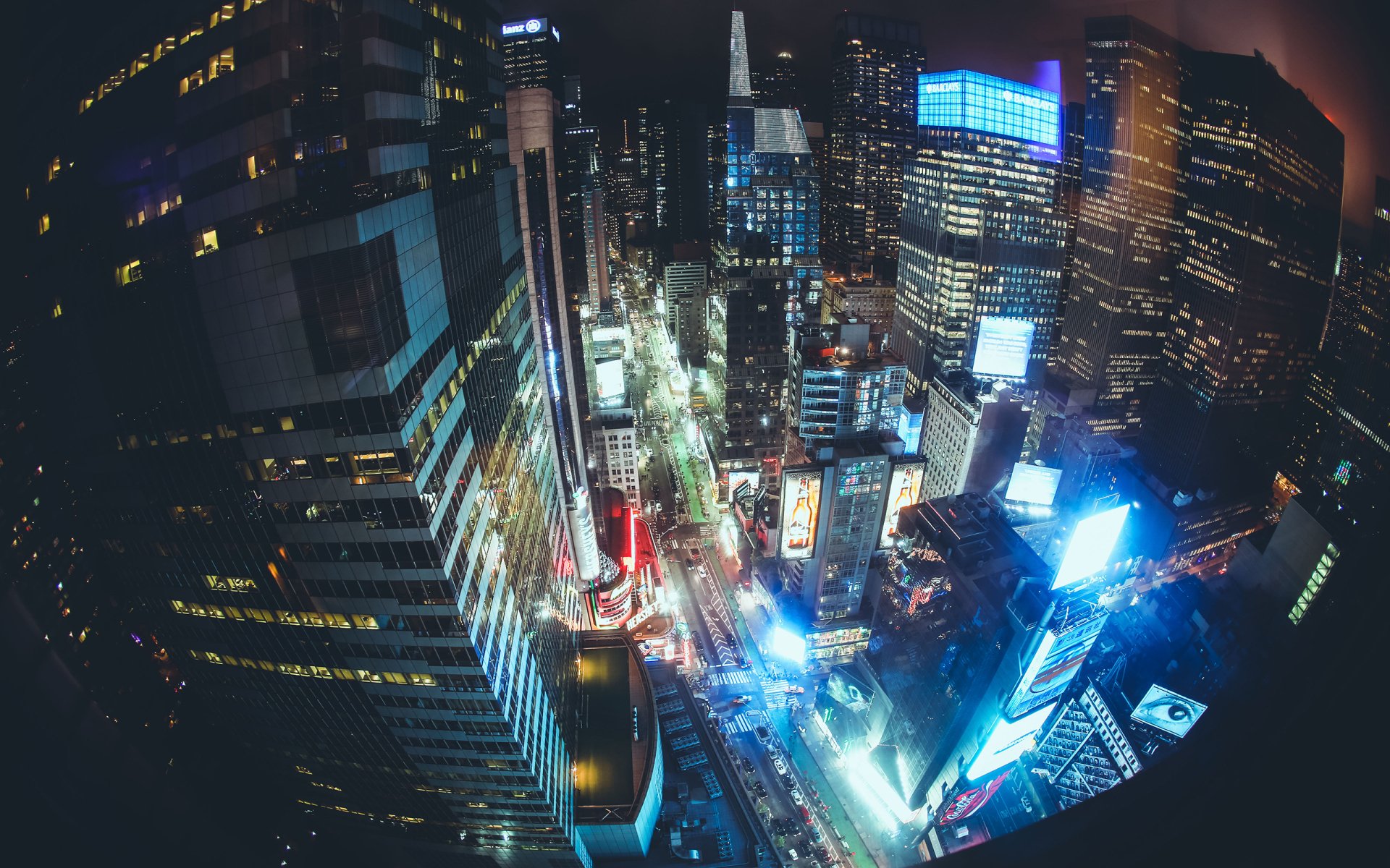 A vibrant cityscape at night captured with a fisheye lens, showcasing illuminated buildings and bustling streets, creating a stunning HD wallpaper for desktops.