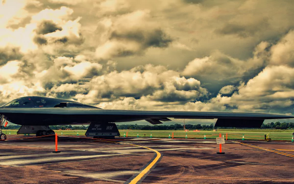 HD PC desktop wallpaper: Northrop B-2 Spirit stealth bomber, a military flying-wing warplane on wet tarmac beneath dramatic, stormy clouds.
