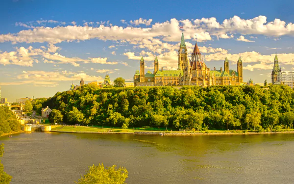 A vibrant 4K Ultra HD image of Parliament Hill's iconic architecture in Ottawa, Ontario, Canada, set against a bright sky and lush greenery along the river.