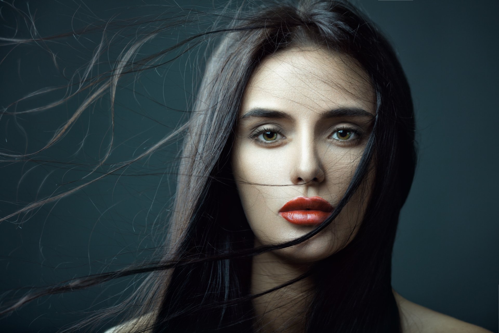Close-up of a brunette woman with red lipstick, strands of hair flowing across her face, captured in 4K Ultra HD quality for a PC desktop wallpaper.