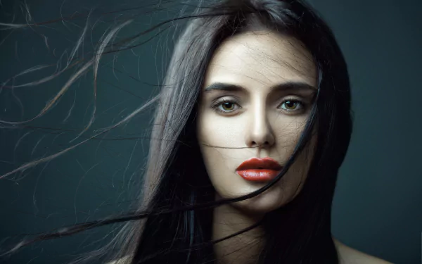 Close-up of a brunette woman with red lipstick, strands of hair flowing across her face, captured in 4K Ultra HD quality for a PC desktop wallpaper.