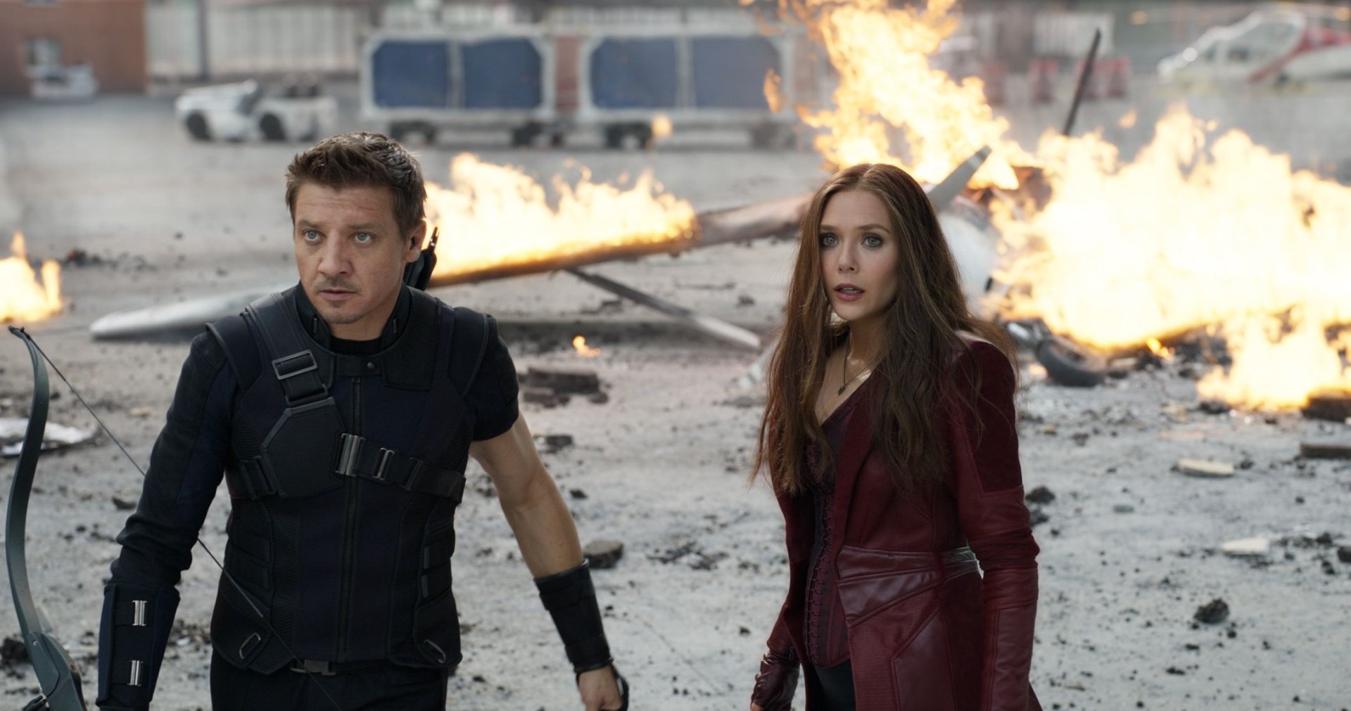 Elizabeth Olsen and Jeremy Renner portray Scarlet Witch and Hawkeye in a dramatic scene from Captain America: Civil War, set against a fiery backdrop. High-definition wallpaper.
