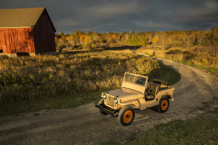 4K Ultra HD desktop wallpaper featuring a classic military Willys MB Jeep on a winding dirt road near a red barn under a dramatic sky.