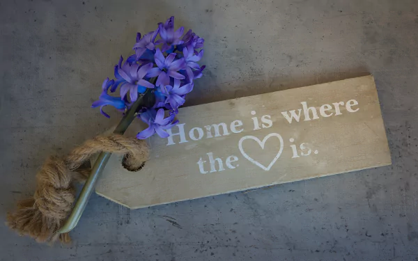HD desktop wallpaper featuring a purple hyacinth with a rustic tag that reads Home is where the ♥ is, blending themes of love and heart in a floral statement.
