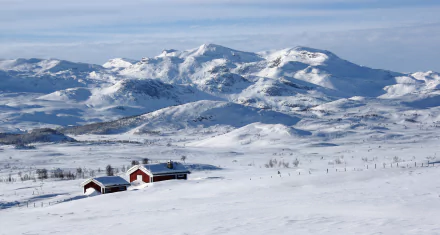 Snowy Norwegian mountain landscape with red houses nestled in white winter snow — 2K Quad HD PC desktop wallpaper and background.