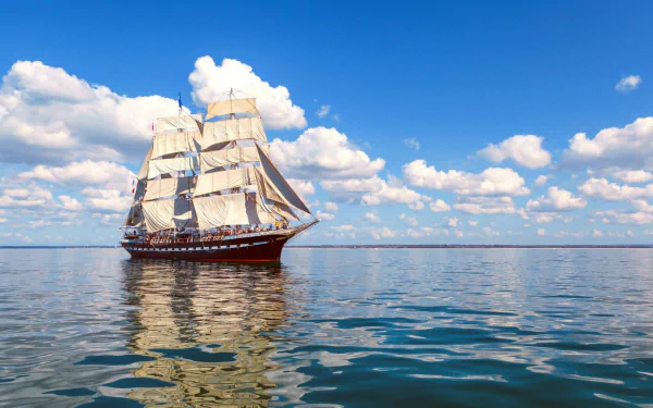 HD PC desktop wallpaper: tall-masted schooner sailboat ship, a classic marine vehicle, gliding on calm sea beneath a bright blue sky with scattered clouds.