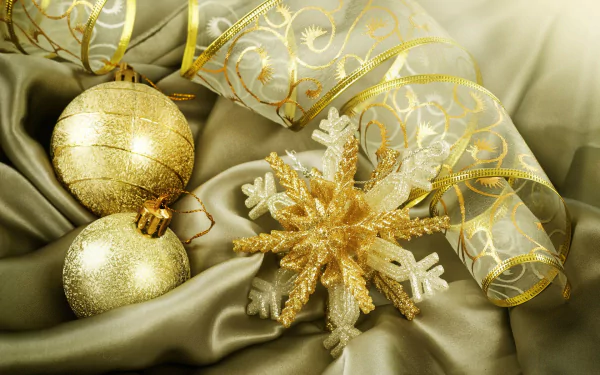 HD desktop wallpaper featuring gold Christmas ornaments and a glittering snowflake on luxurious satin fabric with elegant holiday ribbon accents.