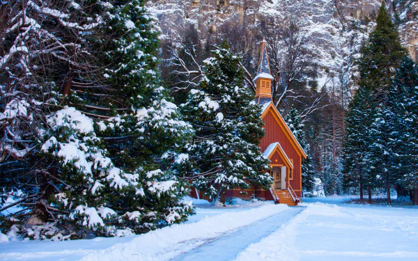 Snow-covered trees surround a small wooden chapel in a serene winter landscape, captured in HD for a peaceful desktop wallpaper and background.