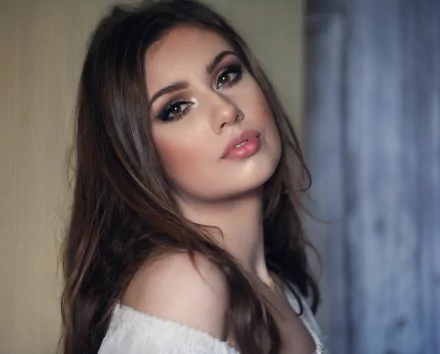 HD desktop wallpaper featuring a close-up portrait of a brunette woman with brown eyes, styled as a model, against a softly lit background.