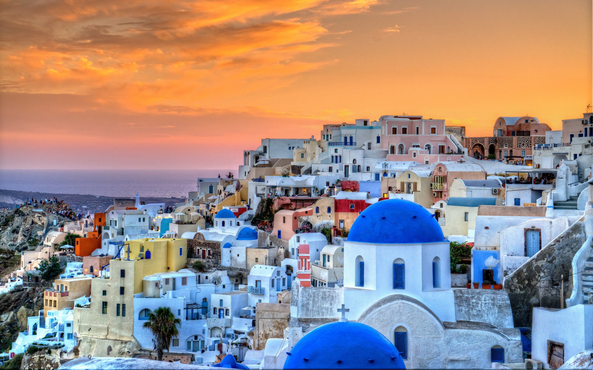 Sunset over the iconic blue-domed houses of Santorini, Greece, showcasing vibrant man-made architecture in this HD desktop wallpaper and background.