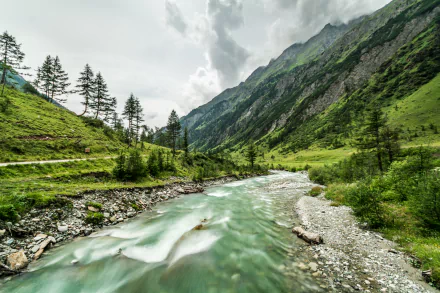 4K Ultra HD wallpaper of a lush green valley with a flowing river, surrounded by towering mountains under a cloudy sky, showcasing serene natural landscape beauty.