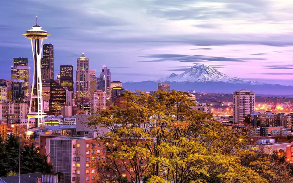 HD desktop wallpaper of Seattle cityscape featuring the Space Needle, surrounding buildings, and a mountain backdrop under a colorful sky.