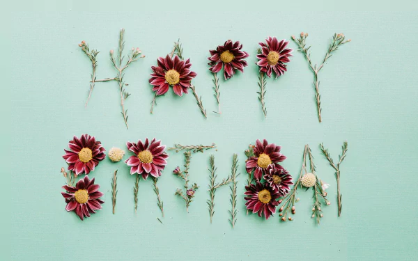 A minimalist HD desktop background featuring the words Happy Birthday creatively arranged with flowers and greenery, set against a soothing mint green backdrop.