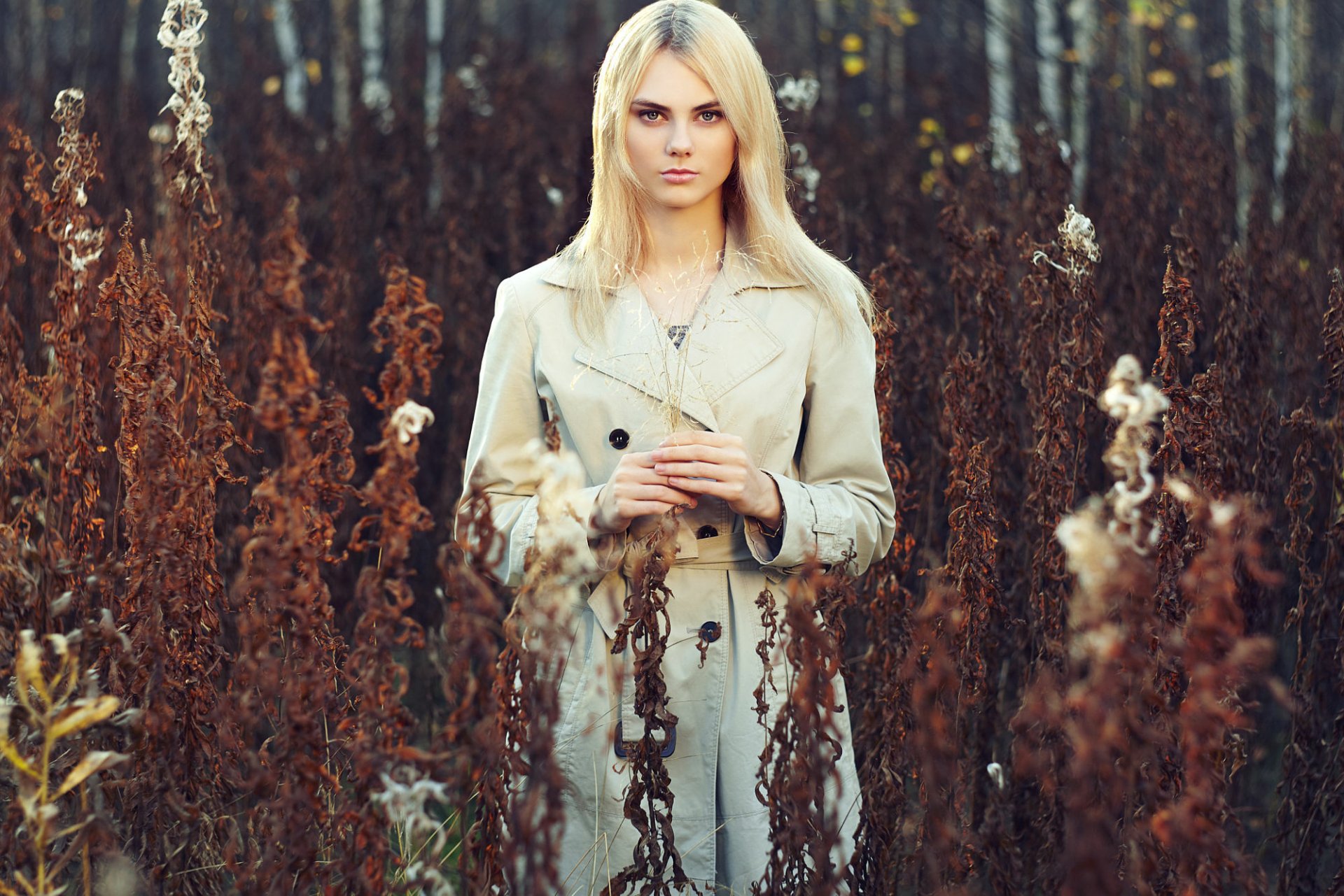 Blonde woman model standing outdoors among tall, dried plants, captured in HD for a PC desktop wallpaper and background.