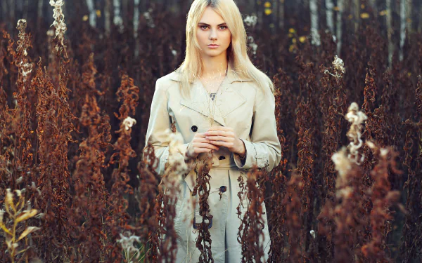 Blonde woman model standing outdoors among tall, dried plants, captured in HD for a PC desktop wallpaper and background.