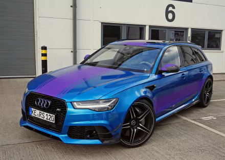 An Audi RS6 showcased in striking blue and purple hues, parked in an industrial setting, captured in stunning 4K Ultra HD for a dynamic desktop background.