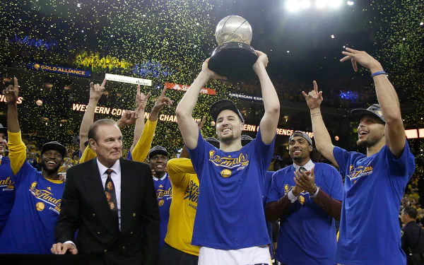A vibrant HD wallpaper featuring the Golden State Warriors celebrating a championship victory, with players lifting a trophy amidst confetti and cheers.