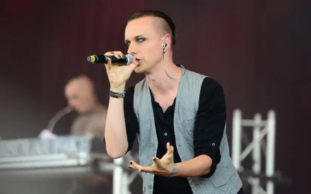 HD PC desktop wallpaper: male singer in a vest with in-ear monitors sings into a microphone onstage, moody synthpop concert vibe; tags: music, Solar Fake.