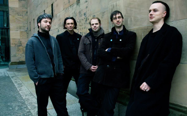 HD desktop wallpaper of five musicians in gothic attire posed against a stone wall — a moody band portrait evoking the gothic sound of Zeraphine.