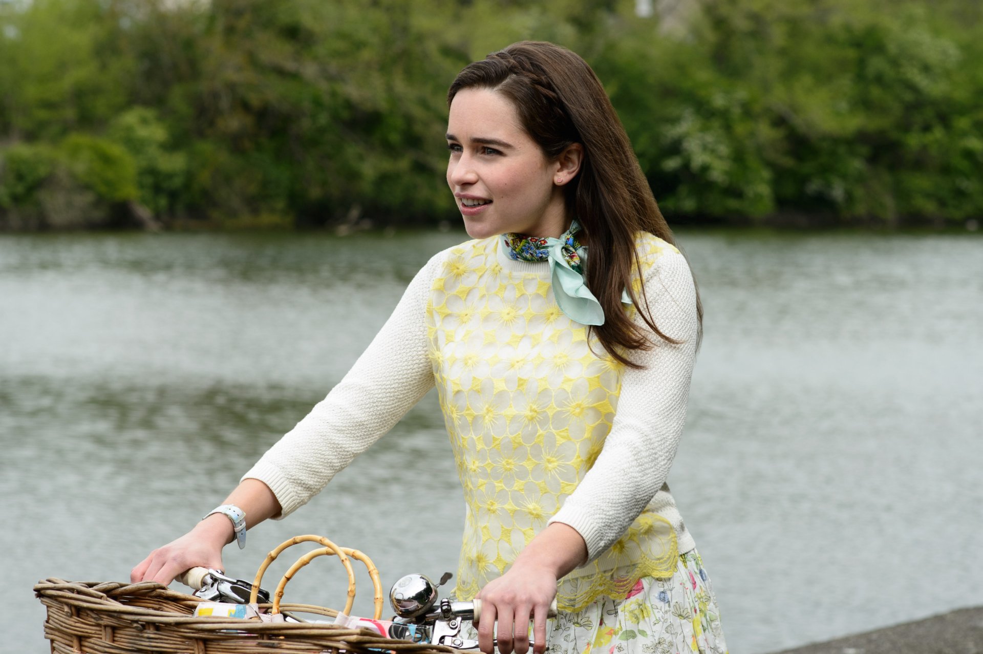 Emilia Clarke as Louisa Clark from the movie Me Before You, riding a bike by a riverside, featured in an HD PC desktop wallpaper.