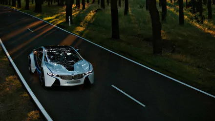 A sleek BMW i8 drives along a winding road, surrounded by trees, creating a striking HD PC desktop wallpaper and background. The vibrant contrast highlights the car's futuristic design.