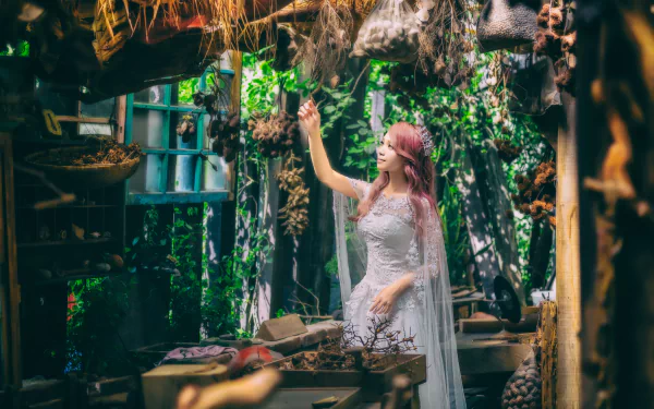 An elegant Asian bride in a white wedding dress is posing in a rustic, nature-filled setting, with greenery and decorative items around her, creating a stunning HD desktop wallpaper and background.