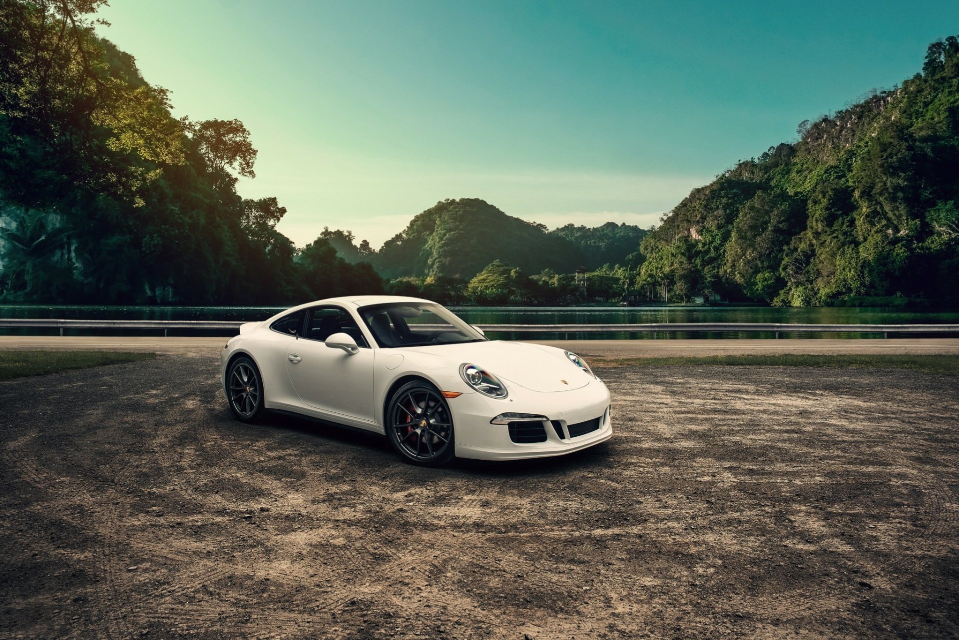 White Porsche 911 sports car on an open asphalt lot with green hills and a teal sky — HD PC desktop wallpaper background showcasing a Porsche vehicle.