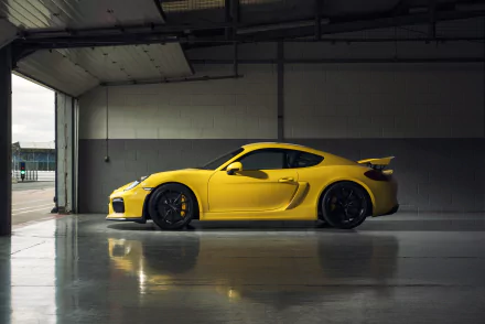 Yellow Porsche Cayman GT4 parked inside a garage, captured in high-resolution 4K Ultra HD for a striking PC desktop wallpaper.