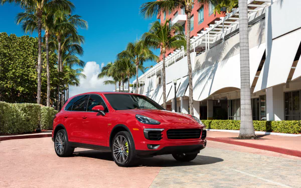 Red Porsche Cayenne SUV vehicle parked by palm trees and modern buildings — 4K Ultra HD PC desktop wallpaper background.