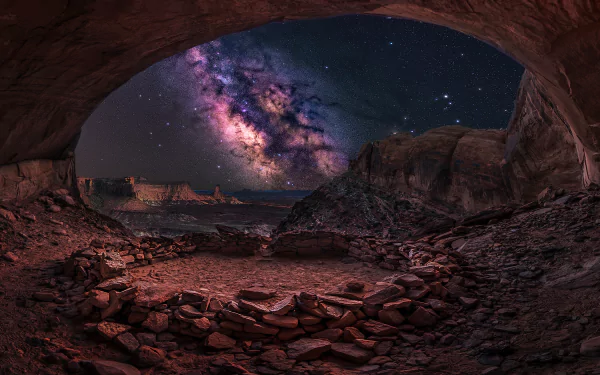 A breathtaking HD wallpaper showcasing a starry night sky with the Milky Way, as seen from inside a rocky cave, highlighting the beauty of nature.
