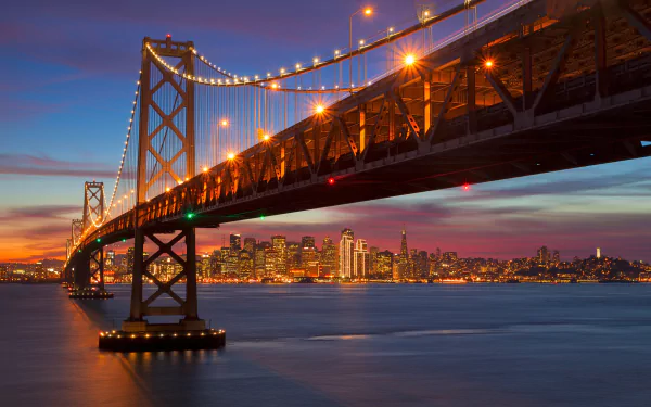 Night view of the illuminated San Francisco Bay Bridge with the city skyline in California, USA, showcased as an HD desktop wallpaper background.