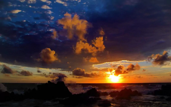 HD desktop wallpaper of a scenic coastline at sunset, featuring ocean waves, a sandy shore, vibrant clouds, and a colorful sky over the sea.