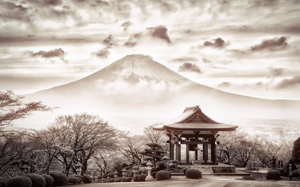 A sepia-toned image of Mount Fuji rising behind a traditional Japanese structure, framed by trees and clouds, capturing the serene beauty of nature in Japan.