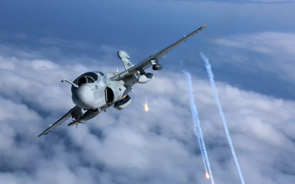 Northrop Grumman EA-6B Prowler jet fighter warplane releasing flares above clouds, captured in 4K Ultra HD military aircraft wallpaper.
