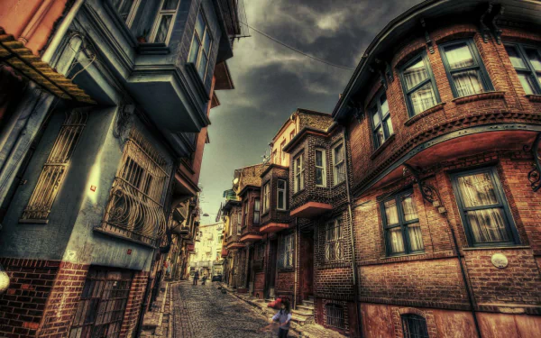 HDR photograph of a narrow city street in Turkey, showcasing historic brick buildings with ornate windows under a dramatic cloudy sky, captured as an HD desktop wallpaper.
