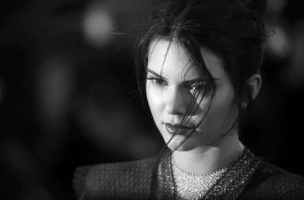 A striking black and white portrait of American model and celebrity Kendall Jenner, showcasing her intense gaze and elegant features against a softly blurred background.