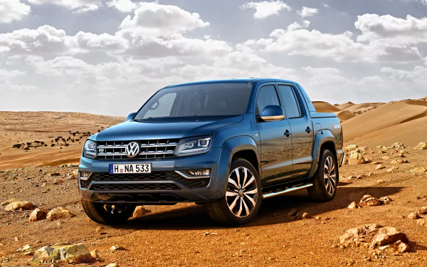 A blue Volkswagen Amarok pickup truck parked on a rocky desert terrain under a partly cloudy sky, featured as a 4K Ultra HD PC desktop wallpaper.