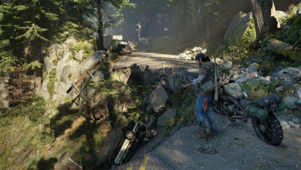 Deacon St. John stands near a damaged road in a dense forest, with a motorcycle nearby and abandoned cars scattered around, capturing a moment from the video game Days Gone.