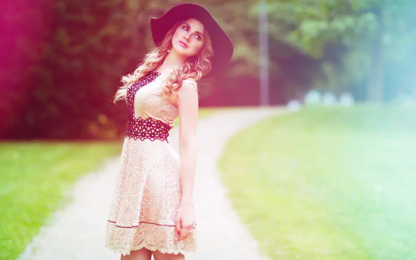A blonde woman with blue eyes and a hat poses outdoors. She is styled as a model, creating a picturesque HD desktop wallpaper and background.