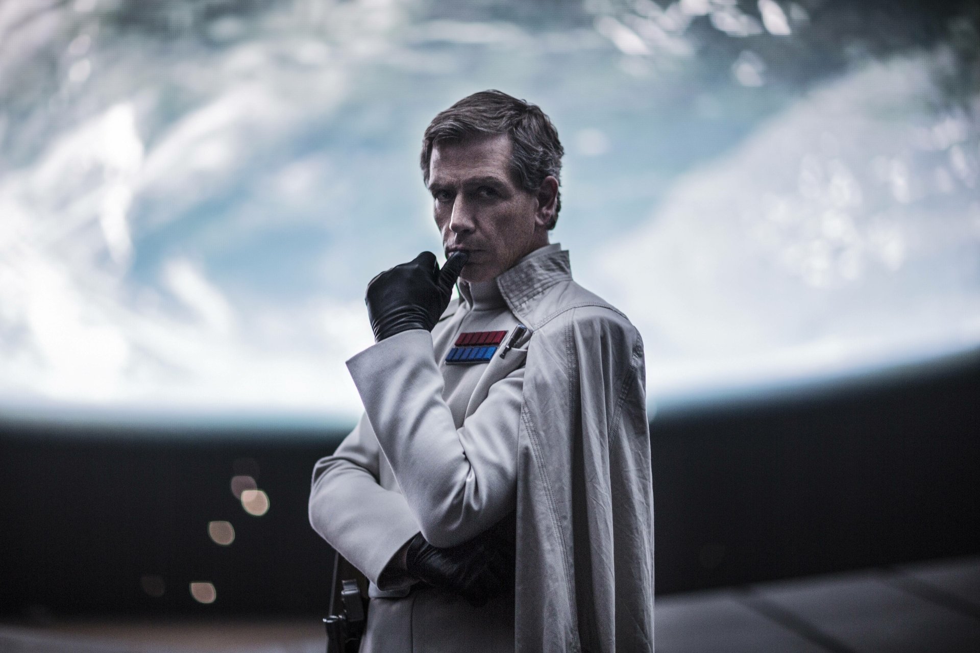 Orson Krennic, portrayed by Ben Mendelsohn, stands with a contemplative expression against a cosmic backdrop in this stunning 4K Ultra HD wallpaper from *Rogue One: A Star Wars Story*.