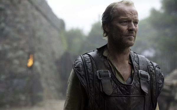 Jorah Mormont from Game of Thrones, brooding in worn leather armor beside a misty stone wall — 4K Ultra HD PC desktop wallpaper.