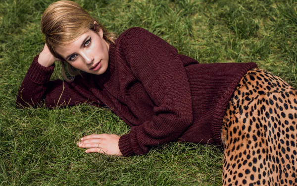 American actress Emma Roberts, a brunette, lies on grass wearing a maroon sweater and leopard print skirt in this HD PC desktop wallpaper and background.