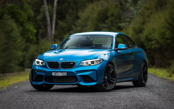 Blue BMW M2 car parked on a forest road, captured in high-definition for a PC desktop wallpaper and background.
