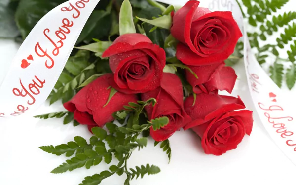 2K Quad HD PC desktop wallpaper: close-up of a man-made red rose bouquet with dew, green ferns and a white I Love You ribbon.