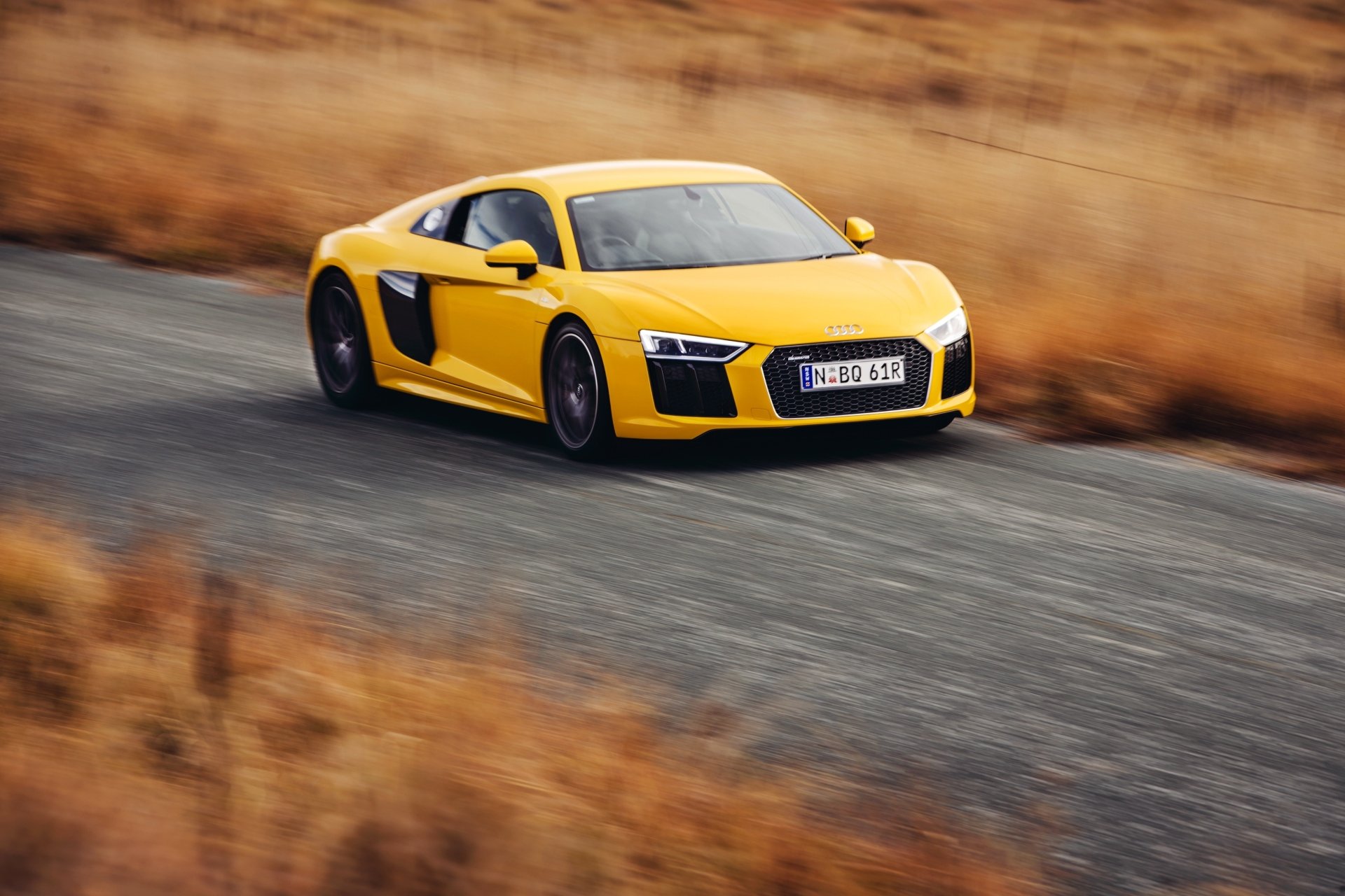 Yellow Audi R8 V10 supercar speeding on a winding road, captured in a sharp 4K Ultra HD desktop wallpaper and background.