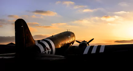 A Douglas C-47 Skytrain military transport aircraft silhouetted against a vibrant sunset, showcasing its historic design and role in aviation. Perfect HD background for enthusiasts.