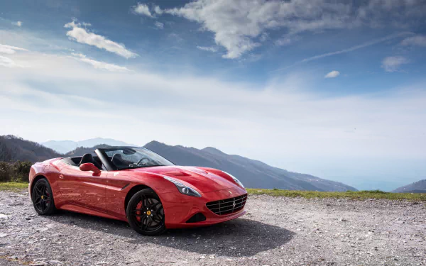 A red Ferrari California T grand tourer parked on a gravel surface with mountains and a cloudy blue sky in the background, rendered in 4K Ultra HD quality.