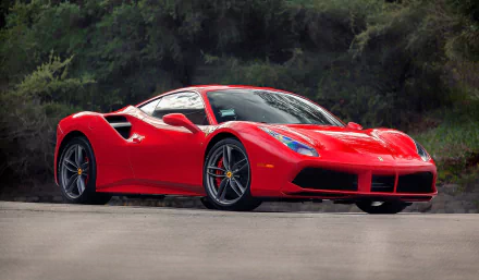 HD desktop wallpaper featuring a vibrant red Ferrari 488 GTB supercar parked on a road with a natural, forested background.